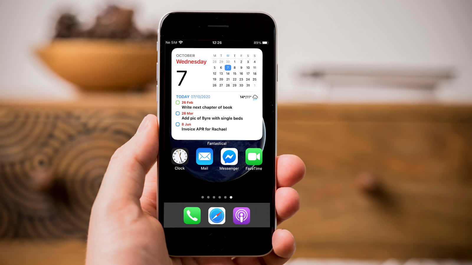 手持iPhone顯示行事曆的人 壁紙