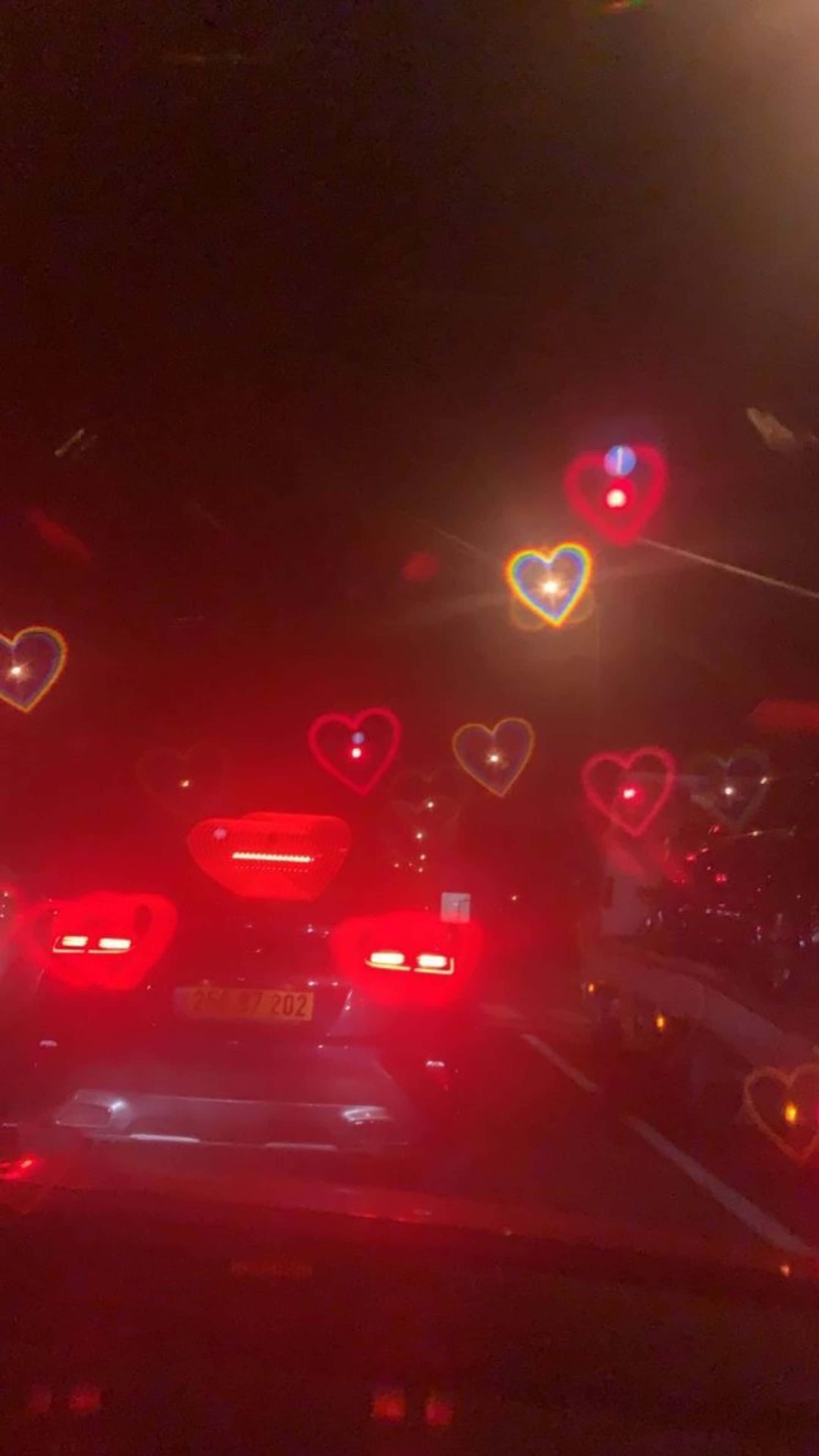 夜晚行駛的汽車，擋風玻璃上有愛心圖案 壁紙