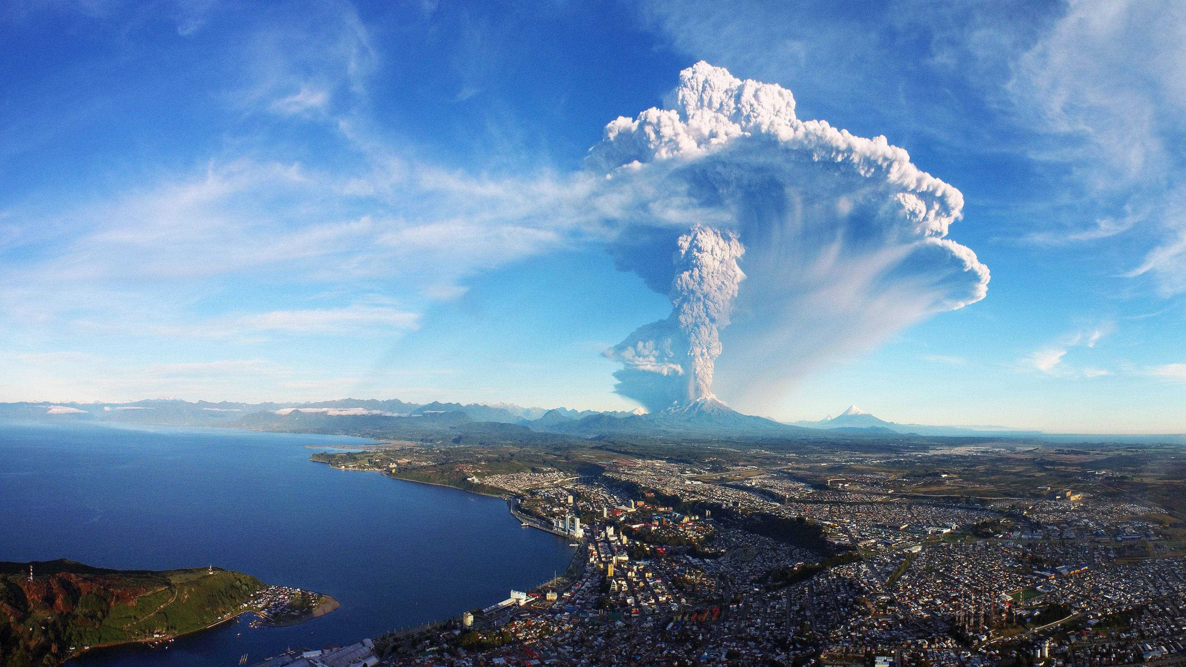 山巒中雄偉噴發的火山 壁紙