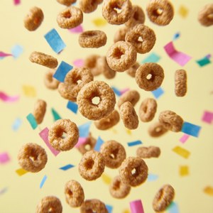 Cheerios像彩纸一样落在淡黄色背景上的俏皮壁纸。 — 华为nova Flip 壁紙