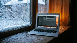 一台MacBook Air置於雪窗邊，室內燈光溫馨。 — MacBook 壁紙