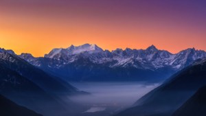 令人惊叹的超广角视角，展现日出时分积雪山脉与雾谷的壮丽景象。
