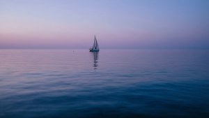 一艘孤帆在黄昏平静的海面上航行。 — 海洋 壁紙