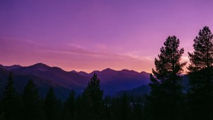 夕陽以紫色色調籠罩山巒，景色令人驚嘆，適合自然愛好者。 — 紫色 壁紙