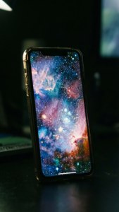 iPhone 17螢幕在黑暗中散發銀河桌布的光芒。