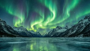 美麗的綠色北極光照亮了雪山之上的夜空。